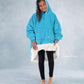 Child wearing The Original Jr. Neon Aqua wearable blanket while showing the CloudSherpa™ lining, highlighting the oversized fit and ultra-cozy construction.