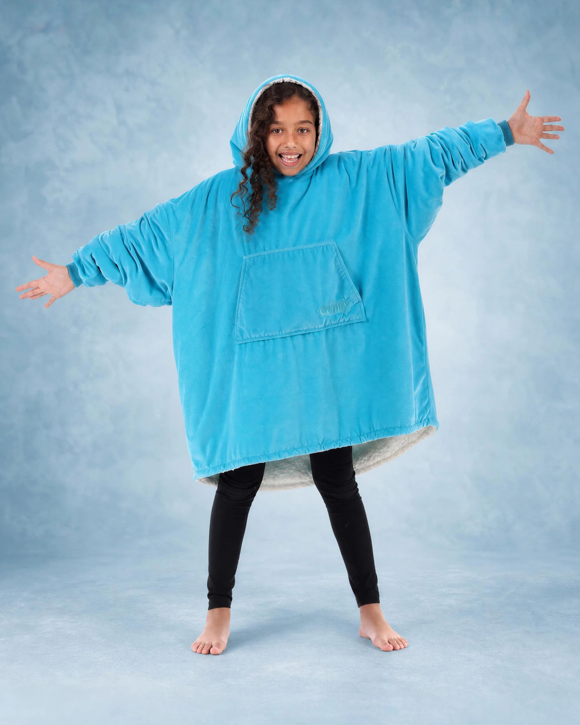 Rear view of a child wearing The Original Jr. Neon Aqua wearable blanket, highlighting the oversized hood and generous coverage.