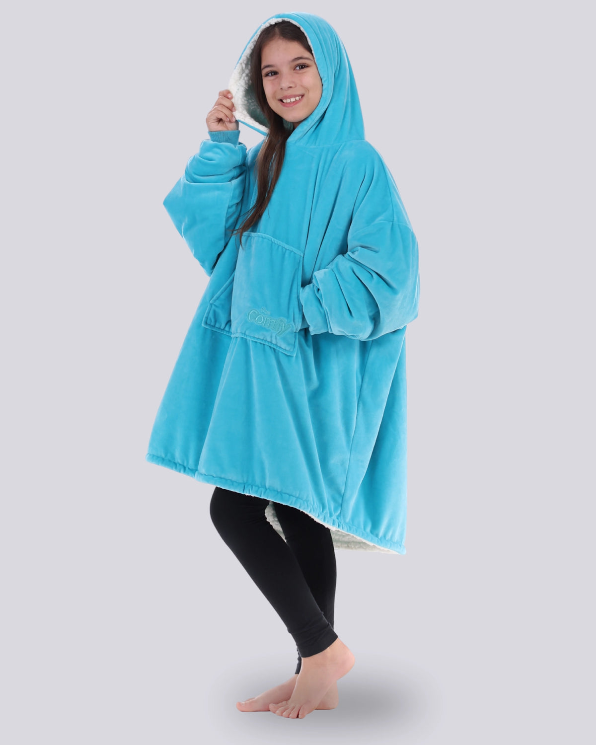 The Original Jr wearable blanket in Neon Aqua, model showing the side view, holding the hood.
