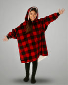 Child wearing The Original Jr. Red Plaid wearable blanket with arms outstretched, demonstrating the roomy oversized design and unrestricted comfort for relaxing or play.