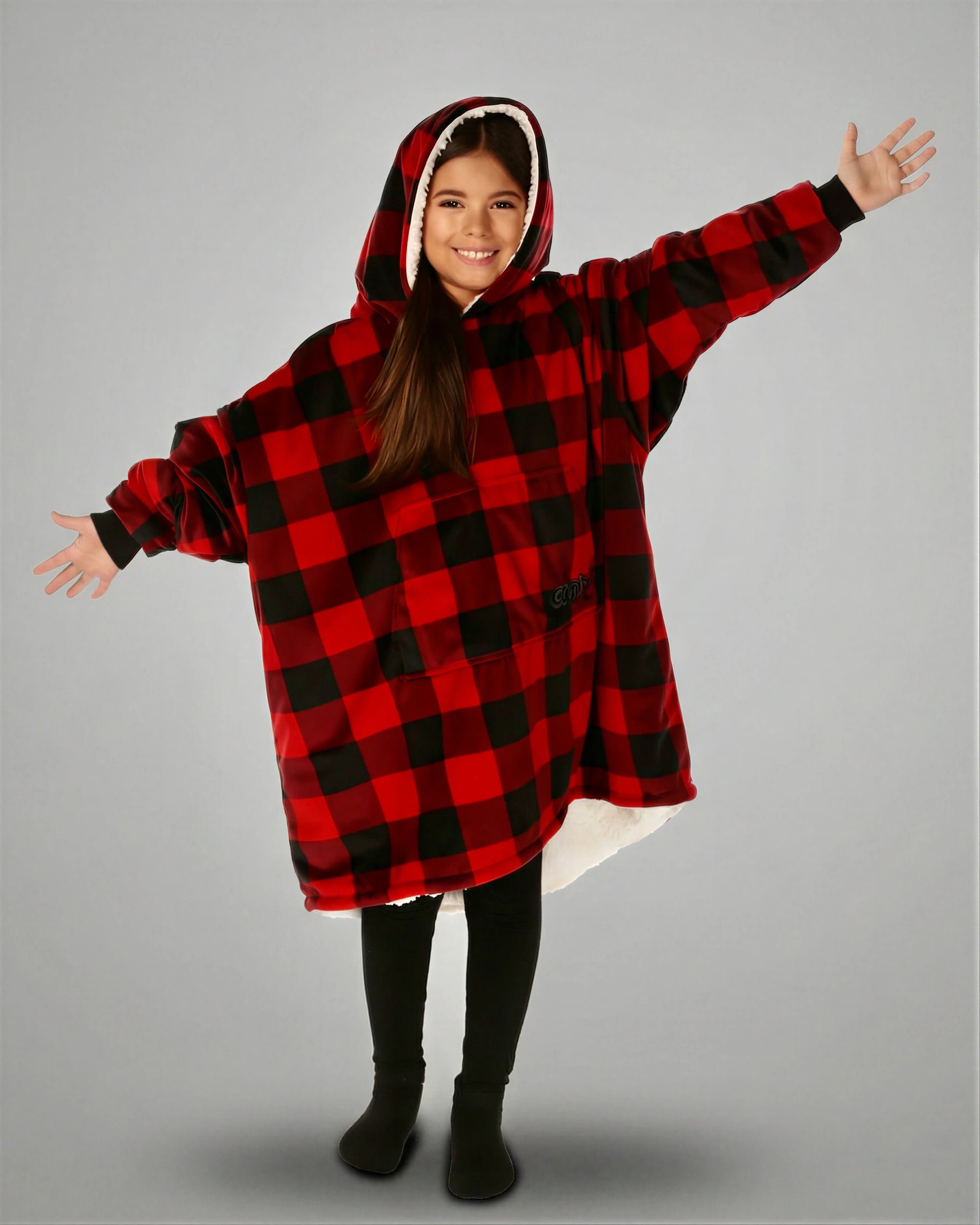 Child wearing The Original Jr. Red Plaid wearable blanket with arms outstretched, demonstrating the roomy oversized design and unrestricted comfort for relaxing or play.