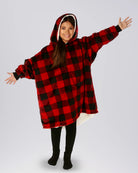 Child wearing The Original Jr. Red Plaid wearable blanket with arms outstretched, demonstrating the roomy oversized design and unrestricted comfort for relaxing or play.