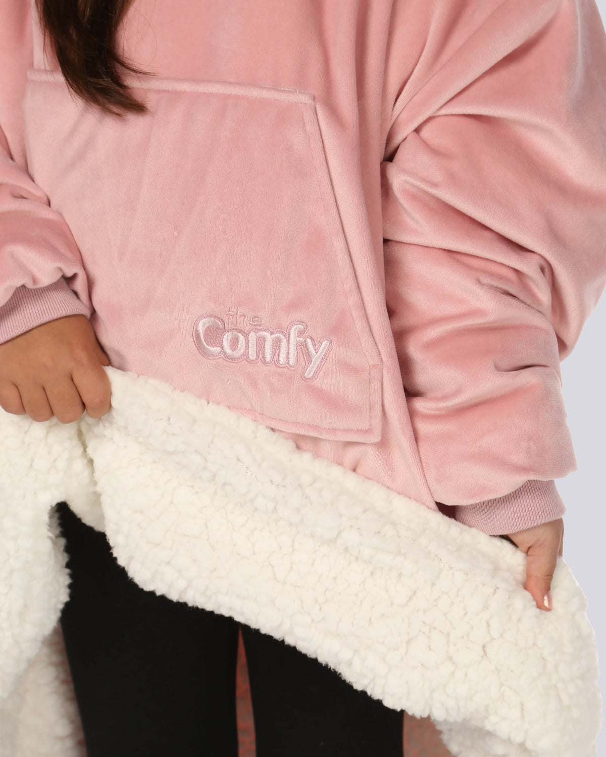 Child wearing The Original Jr. Blush wearable blanket holding up the hem to show the sherpa lining