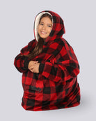 Child wearing The Original Jr. Red Plaid wearable blanket curled up with legs tucked under.