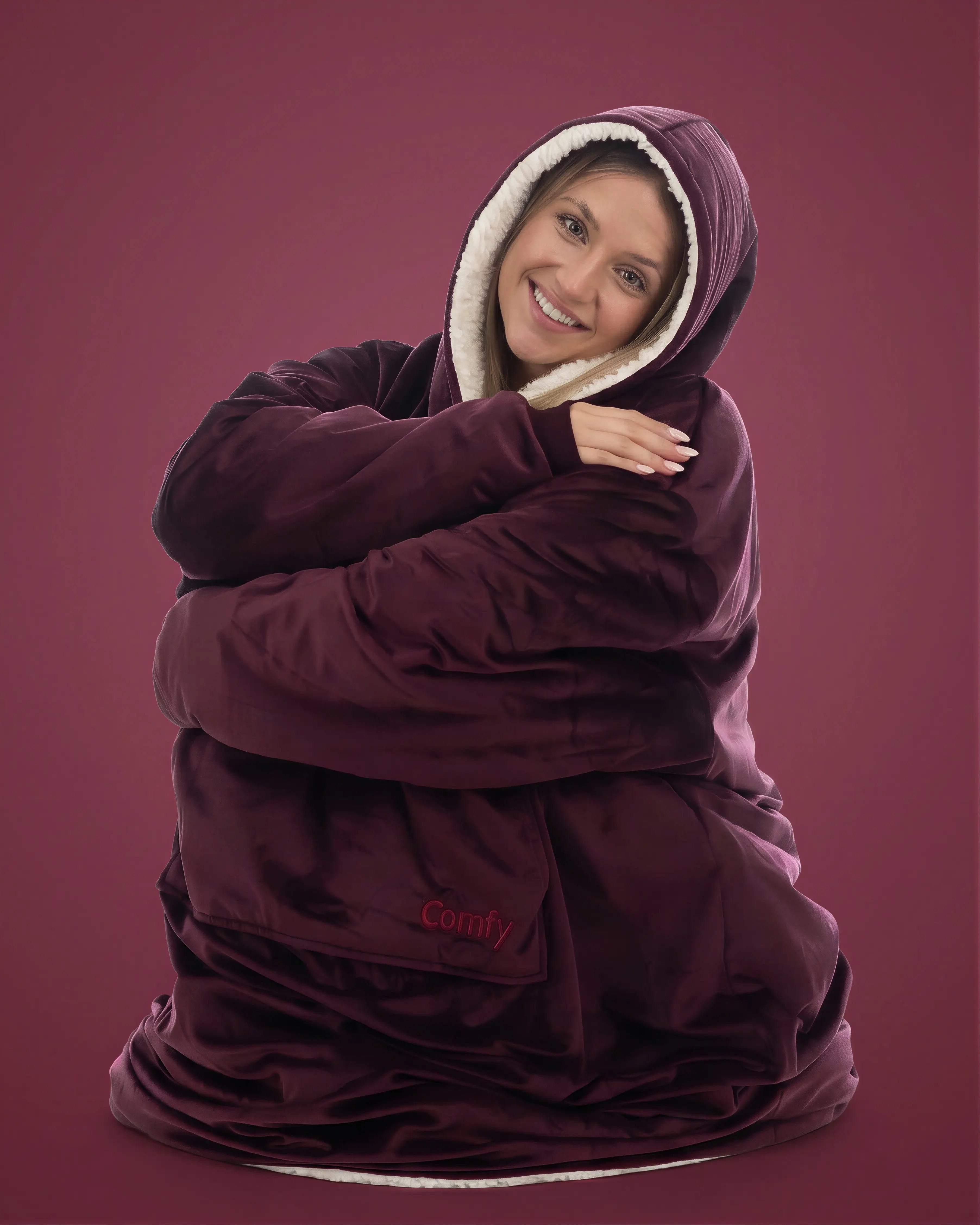 Woman wearing The Comfy Original Long in burgundy, seated comfortably in a relaxed pose.