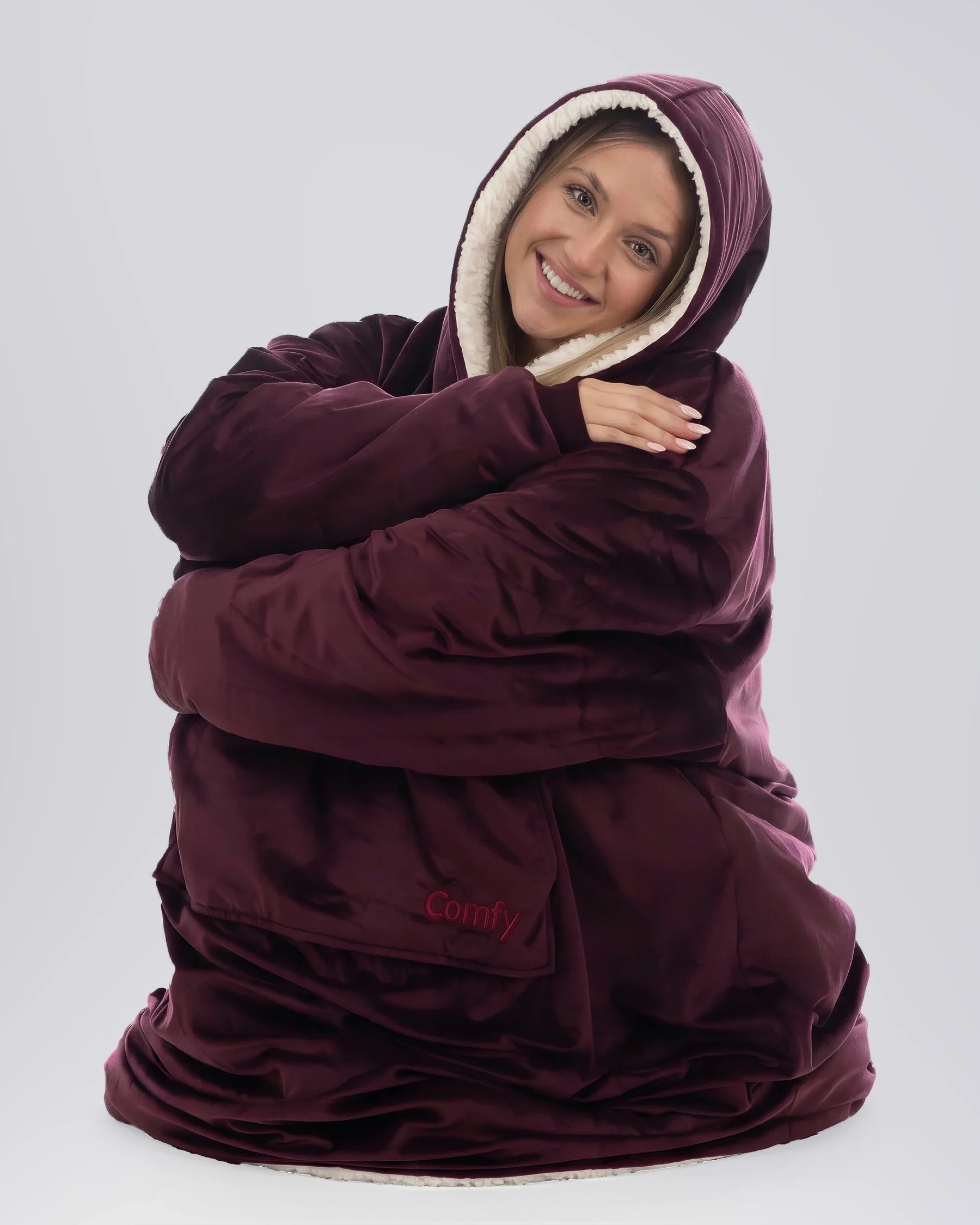 Woman wearing The Comfy Original Long in burgundy, seated comfortably in a relaxed pose.