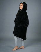 Side view of The Original wearable blanket in black showing oversized fit and hood design