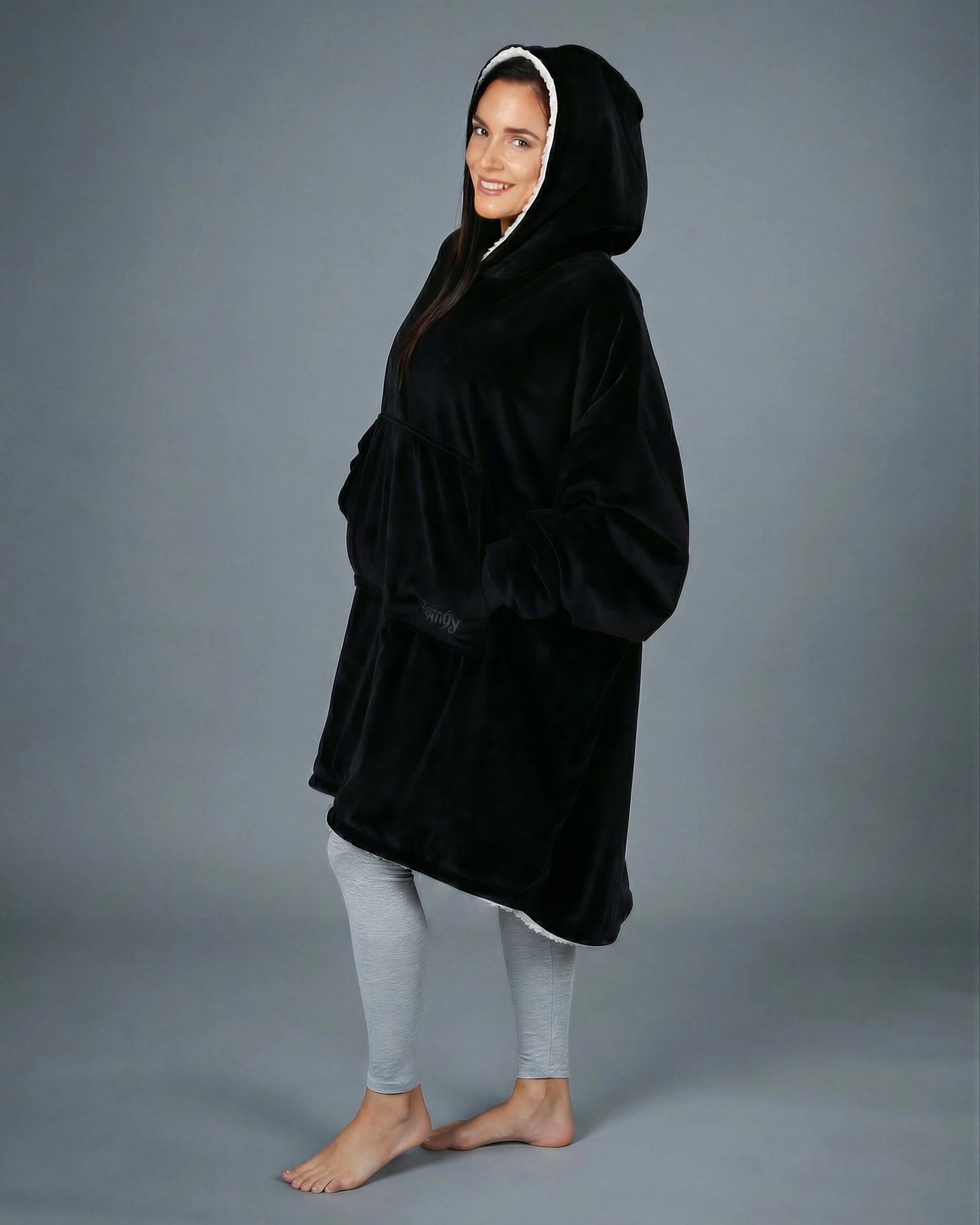 Side view of The Original wearable blanket in black showing oversized fit and hood design