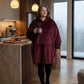 Front view of woman walking through kitchen  showing front view of Original wearable blanket hoodie in burgundy