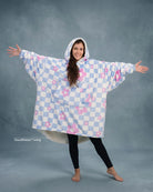 Front-facing hero image of The Original in Flower Checkered, featuring a playful blue-and-white checker pattern with pink floral accents, oversized silhouette, kangaroo pocket, and cozy CloudSherpa™ lining.