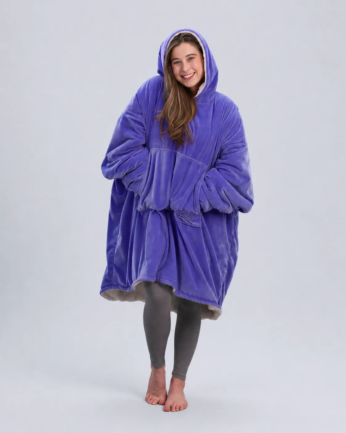 Front-facing lifestyle image of a model wrapped in The Original in Very Perri Purple, emphasizing the oversized fit, plush CloudSherpa™ lining, and cozy hands-in-pocket comfort.