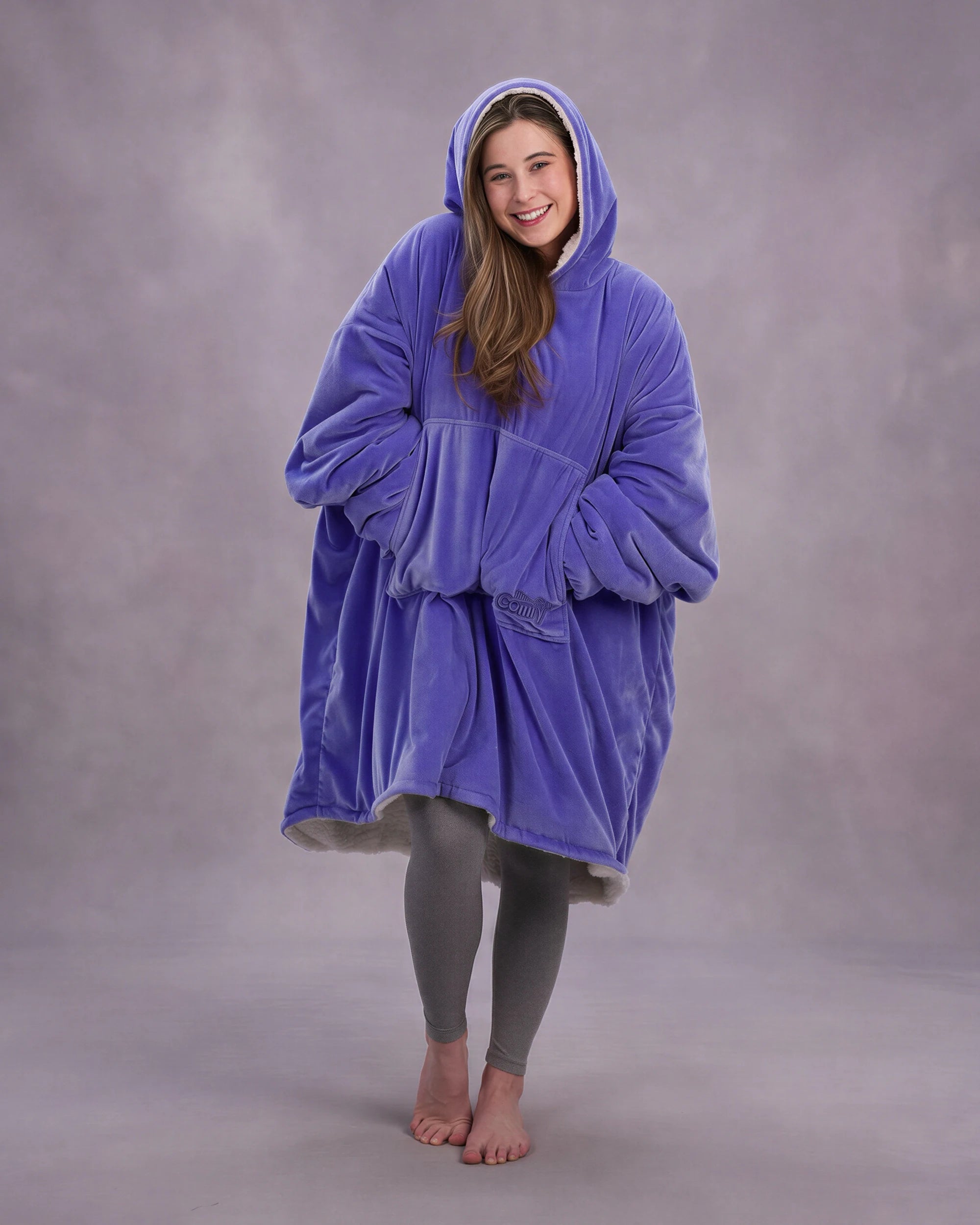 Front-facing lifestyle image of a model wrapped in The Original in Very Perri Purple, emphasizing the oversized fit, plush CloudSherpa™ lining, and cozy hands-in-pocket comfort.