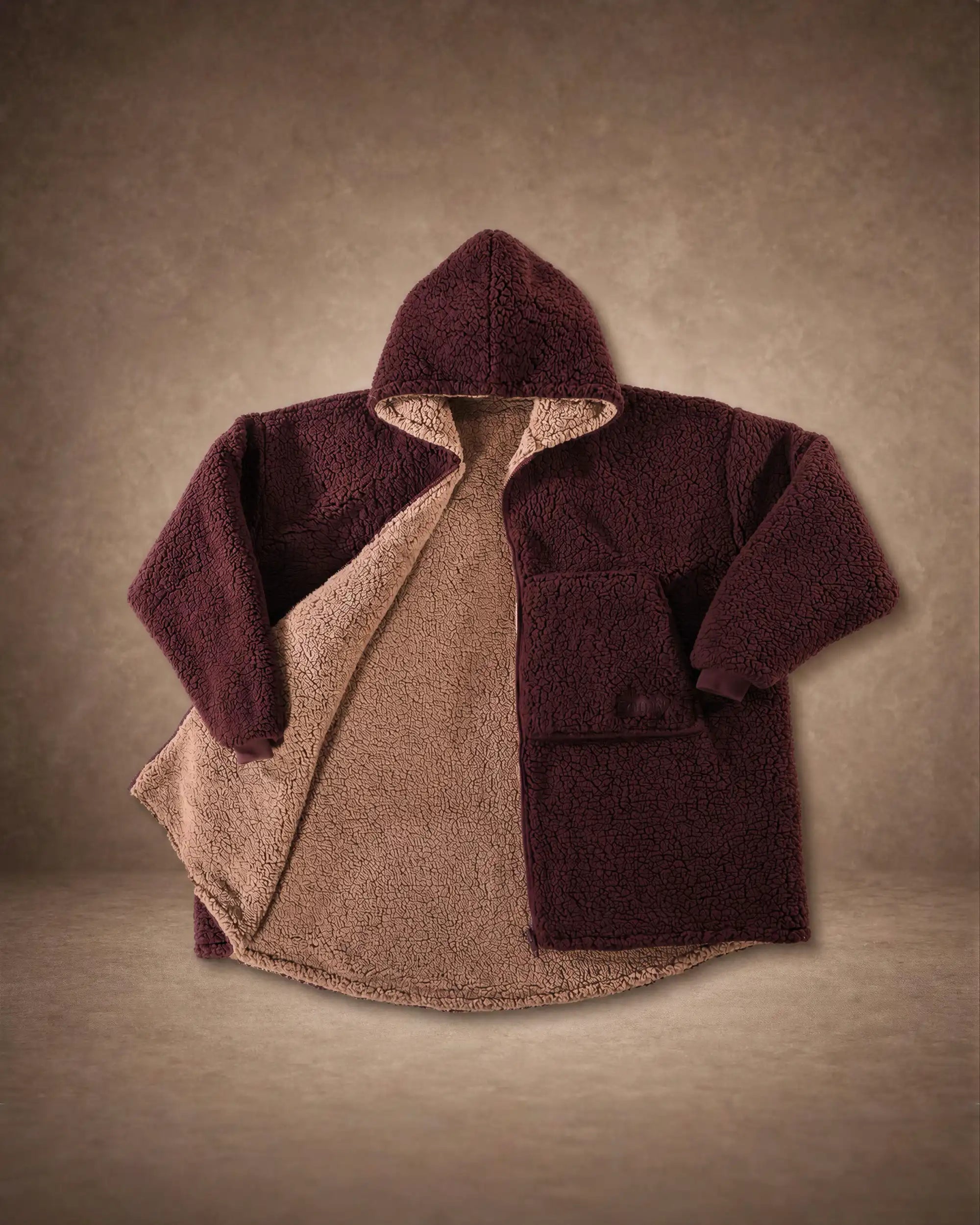 Product flat lay of the Teddy Bear Full-Zip in Chocolate, displaying the reversible CloudSherpa™ interior, oversized hood, and full-zip design.