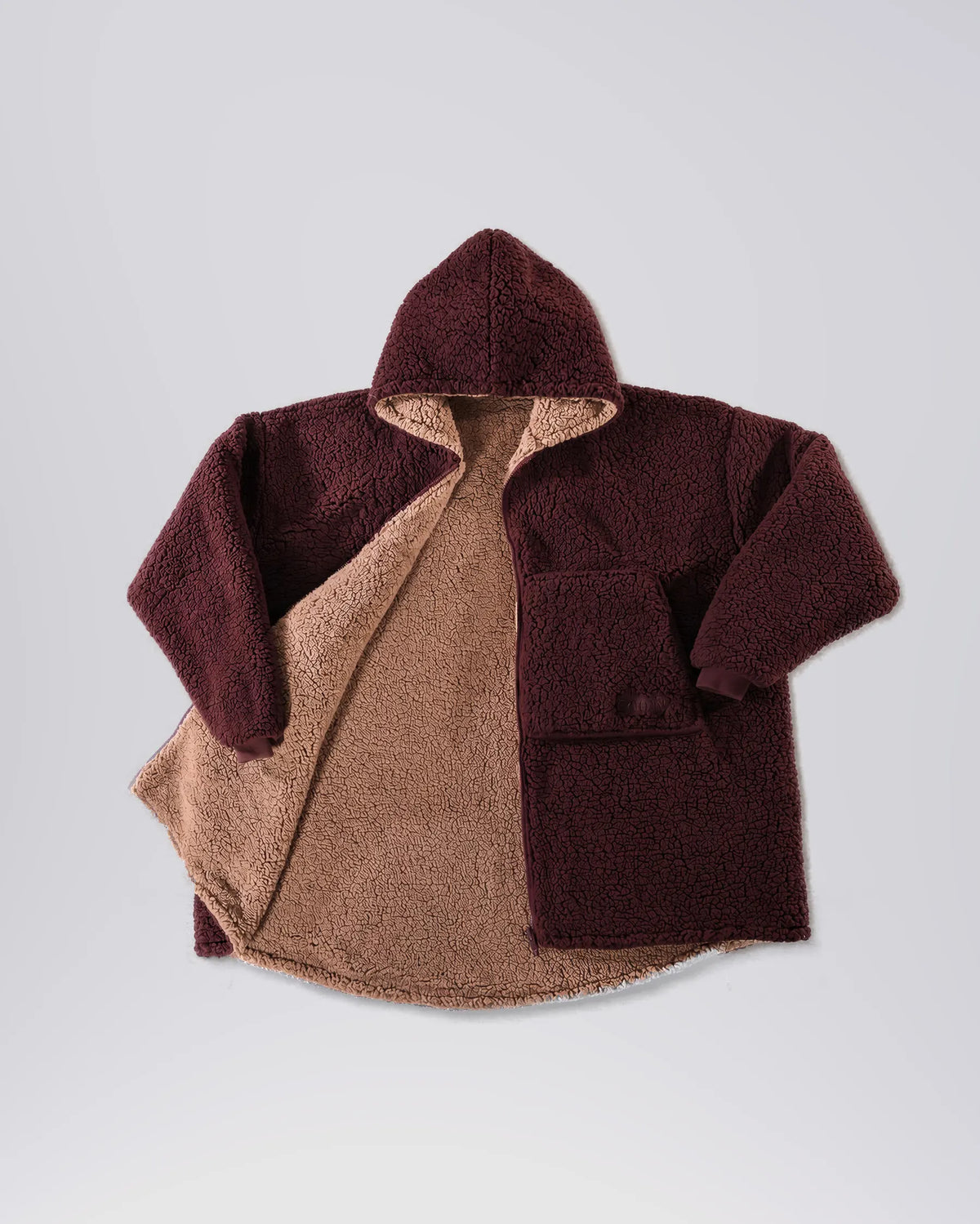 Product flat lay of the Teddy Bear Full-Zip in Chocolate, displaying the reversible CloudSherpa™ interior, oversized hood, and full-zip design.