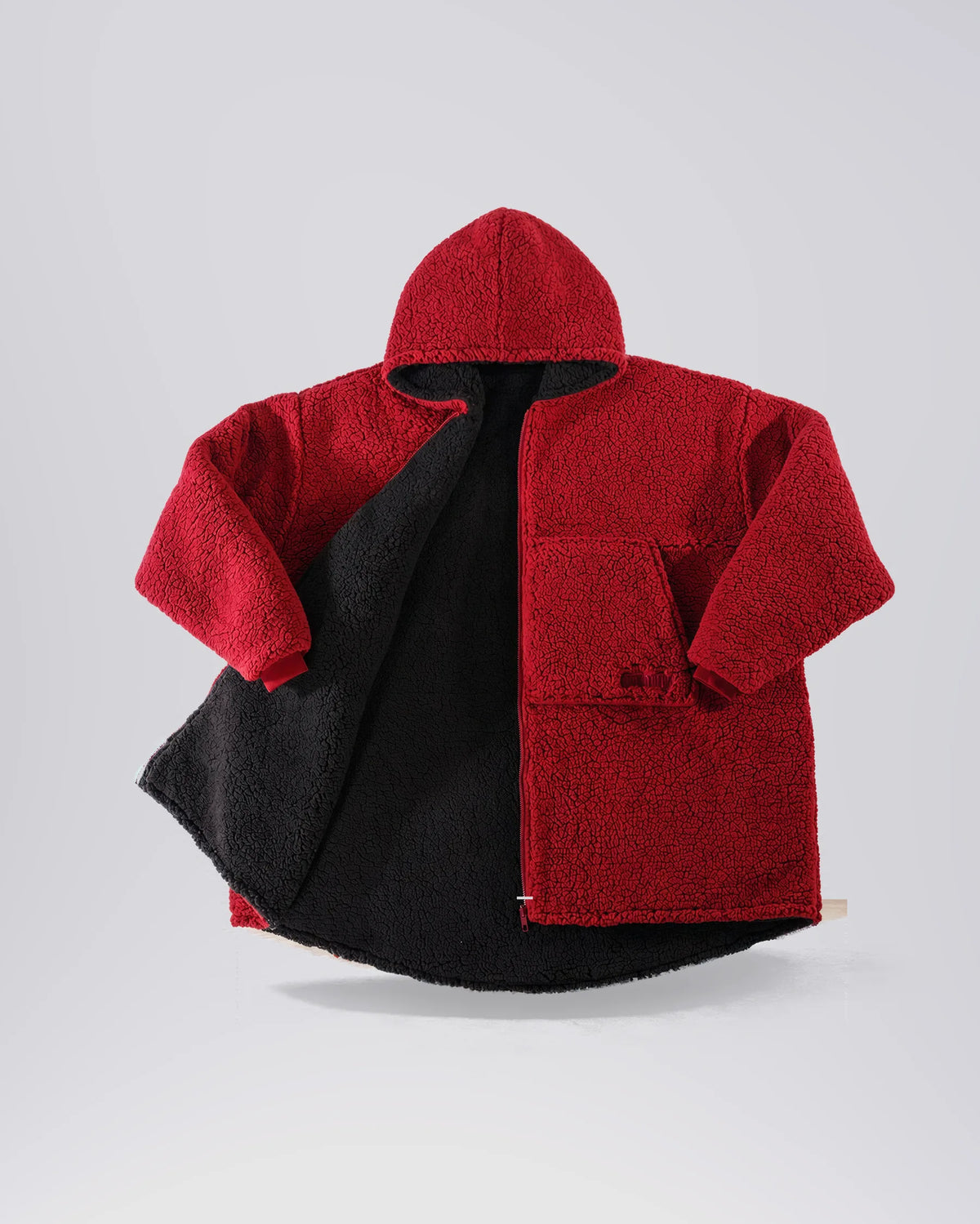Flat lay of The Teddy Bear Full-Zip on its Crimson side, showing the hood, full-length zipper, and plush CloudSherpa™ fabric.
