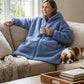 Woman relaxing on a couch in the Teddy Bear Full-Zip worn on the Denim side, showcasing everyday comfort, warmth, and lounging versatility.