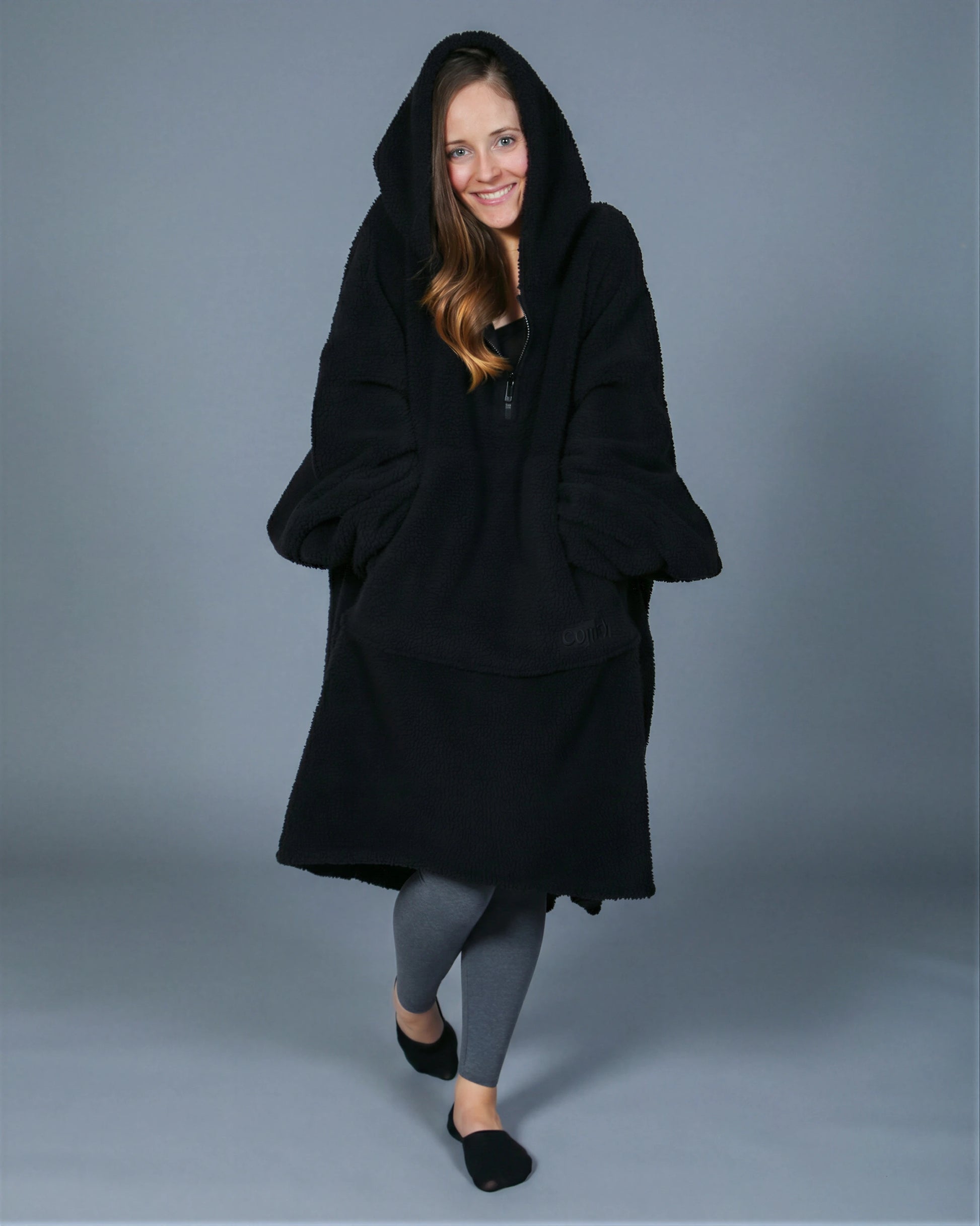 Front view of The Teddy Bear Quarter-Zip wearable blanket in black with hood up showing relaxed silhouette and cozy coverage