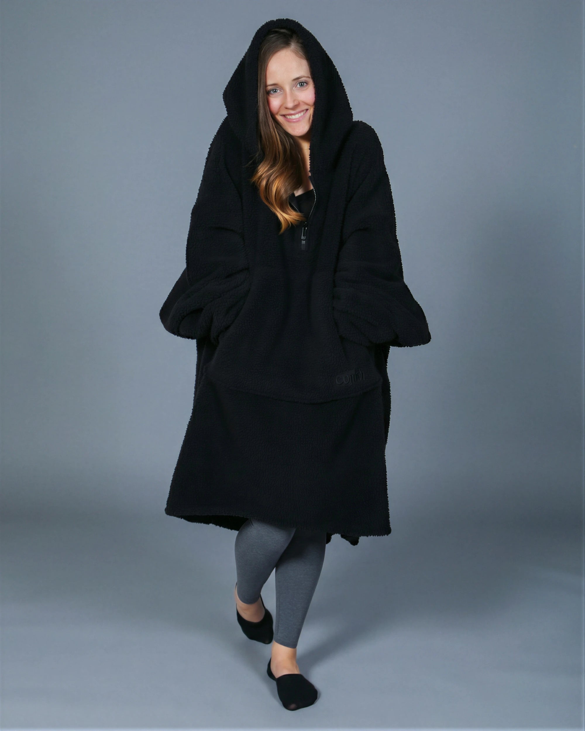 Front view of The Teddy Bear Quarter-Zip wearable blanket in black with hood up showing relaxed silhouette and cozy coverage
