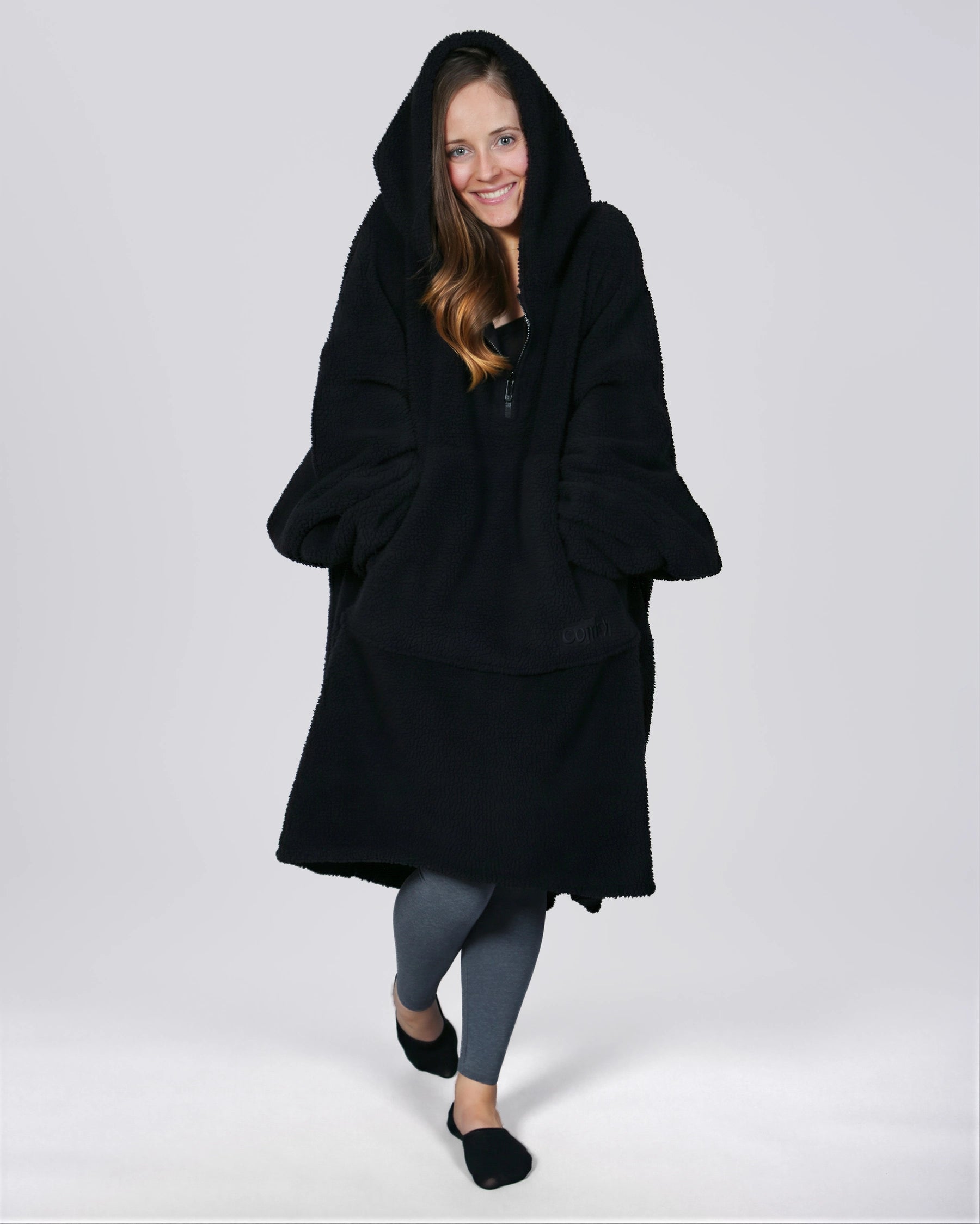 Front view of The Teddy Bear Quarter-Zip wearable blanket in black with hood up showing relaxed silhouette and cozy coverage