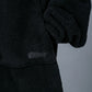 Close-up of The Teddy Bear Quarter-Zip wearable blanket in black showing sleeve detail and embroidered logo on CloudSherpa™ fabric
