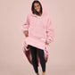 Front view of The Teddy Bear Quarter-Zip wearable blanket in blush with model lifting hem to show full coverage and soft interior
