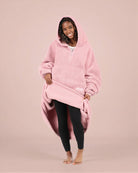 Front view of The Teddy Bear Quarter-Zip wearable blanket in blush with model lifting hem to show full coverage and soft interior