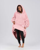 Front view of The Teddy Bear Quarter-Zip wearable blanket in blush with model lifting hem to show full coverage and soft interior