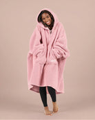 Front view of The Teddy Bear Quarter-Zip wearable blanket in blush with hands in pocket showing oversized sleeves and cozy fit
