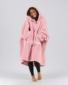 Front view of The Teddy Bear Quarter-Zip wearable blanket in blush with hands in pocket showing oversized sleeves and cozy fit