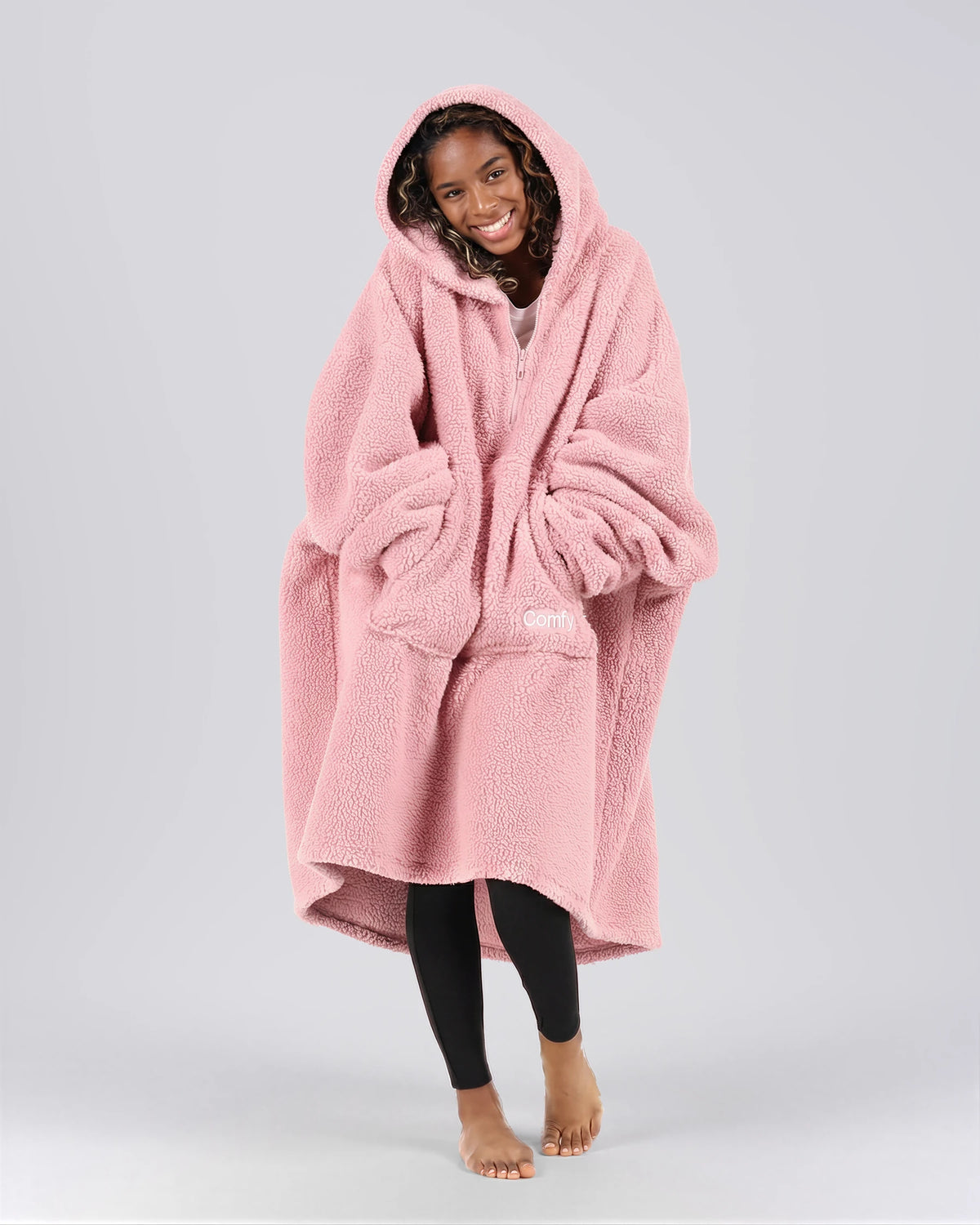 Front view of The Teddy Bear Quarter-Zip wearable blanket in blush with hands in pocket showing oversized sleeves and cozy fit