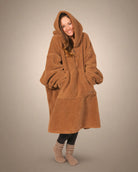 Front view of The Teddy Bear Quarter-Zip wearable blanket in camel showing relaxed oversized silhouette with hood up and hands tucked inside