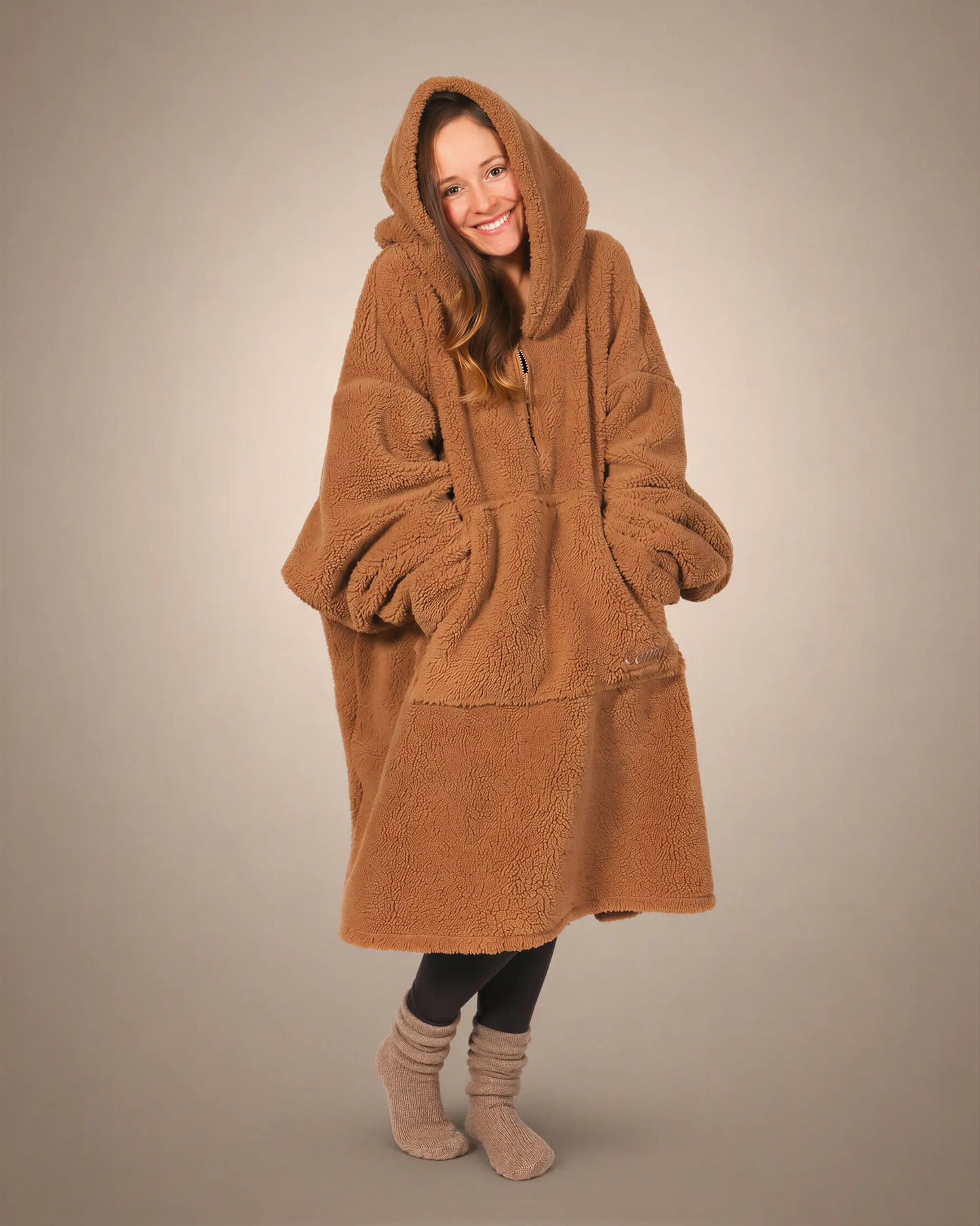 Front view of The Teddy Bear Quarter-Zip wearable blanket in camel showing relaxed oversized silhouette with hood up and hands tucked inside