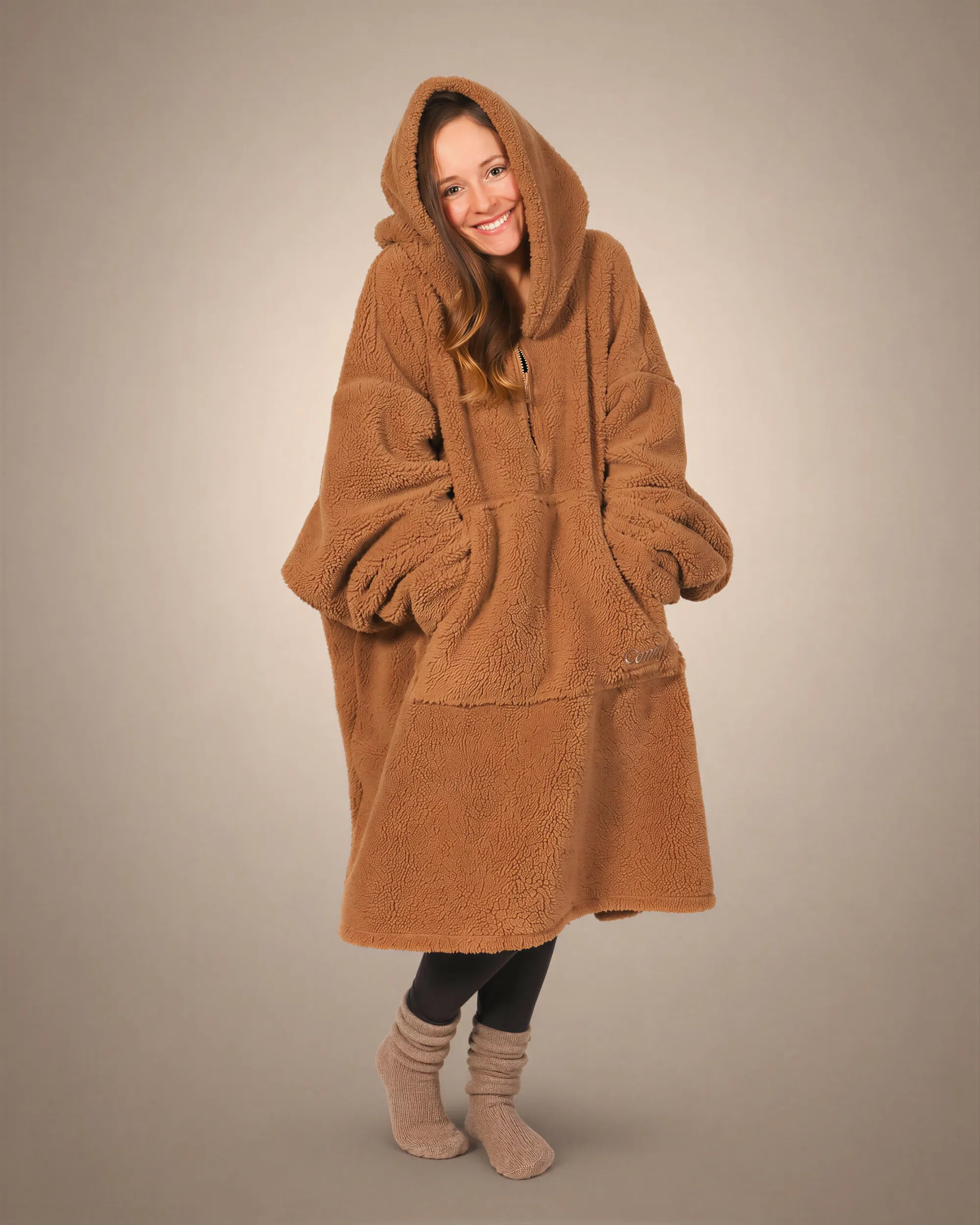 Front view of The Teddy Bear Quarter-Zip wearable blanket in camel showing relaxed oversized silhouette with hood up and hands tucked inside