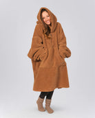 Front view of The Teddy Bear Quarter-Zip wearable blanket in camel showing relaxed oversized silhouette with hood up and hands tucked inside