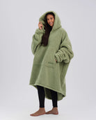Three-quarter view of The Teddy Bear Quarter-Zip wearable blanket in cucumber highlighting relaxed drape, hood, and plush CloudSherpa™ texture