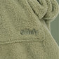 Close-up of The Teddy Bear Quarter-Zip wearable blanket in cucumber showing sleeve detail and embroidered logo on soft CloudSherpa™ fabric