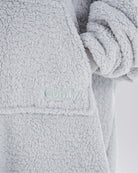 Close-up of The Teddy Bear Quarter-Zip wearable blanket in light gray showing embroidered logo and soft CloudSherpa™ texture
