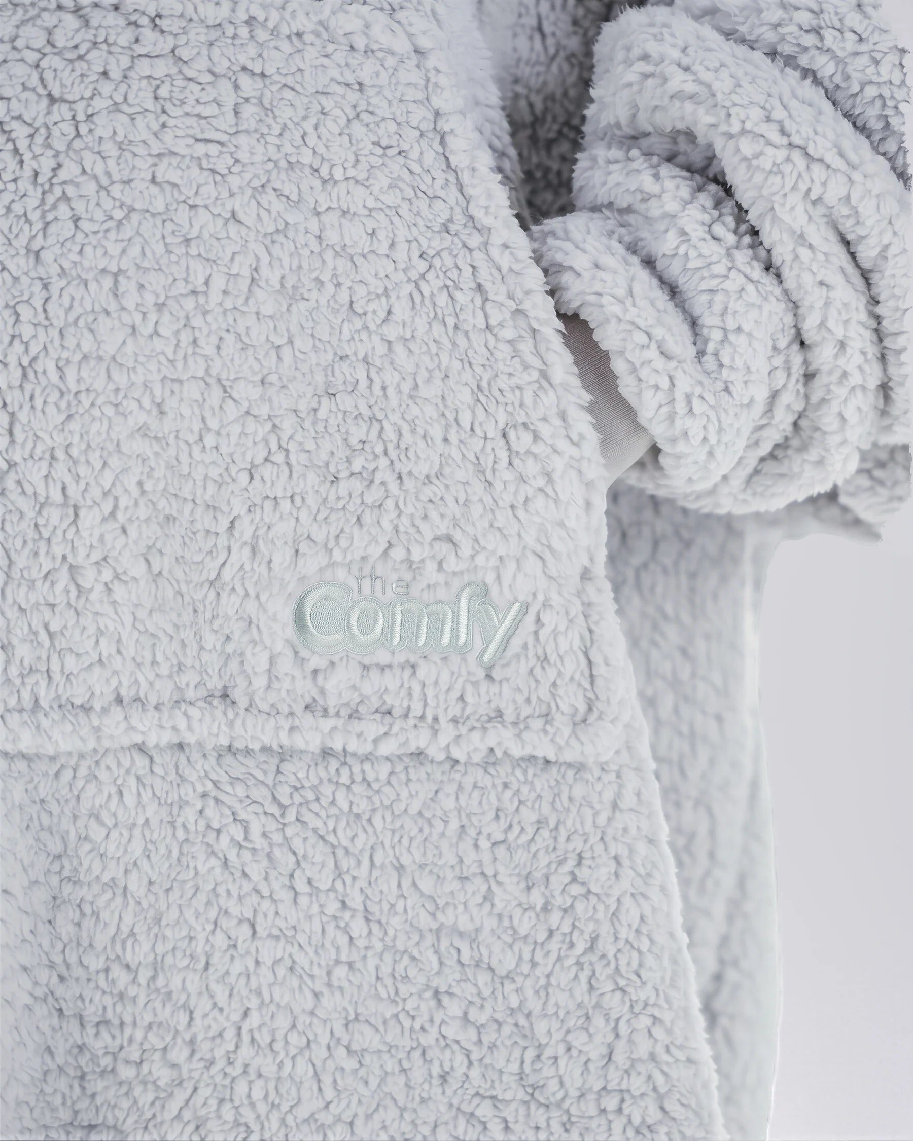 Close-up of The Teddy Bear Quarter-Zip wearable blanket in light gray showing embroidered logo and soft CloudSherpa™ texture