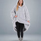 Front view of The Teddy Bear Quarter-Zip wearable blanket in light gray with model lifting hem to show full coverage and plush interior