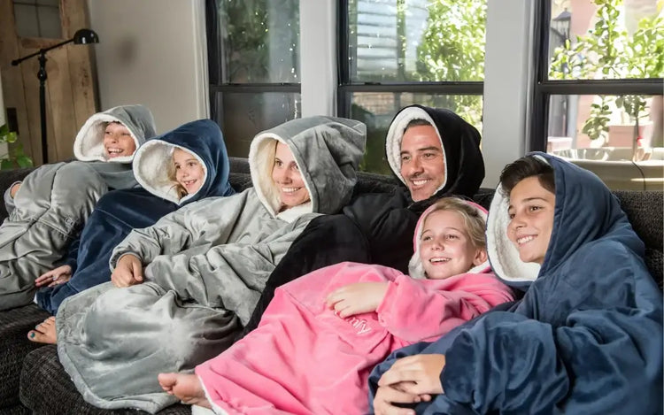 Family of six, four kids and two adults wearing The comfy wearable blankets and smiling