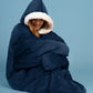 Woman sitting wrapped in The Original wearable blanket in blue showing oversized comfort and warmth
