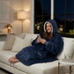 Woman wearing The Original wearable blanket in blue relaxing on a couch while using a phone