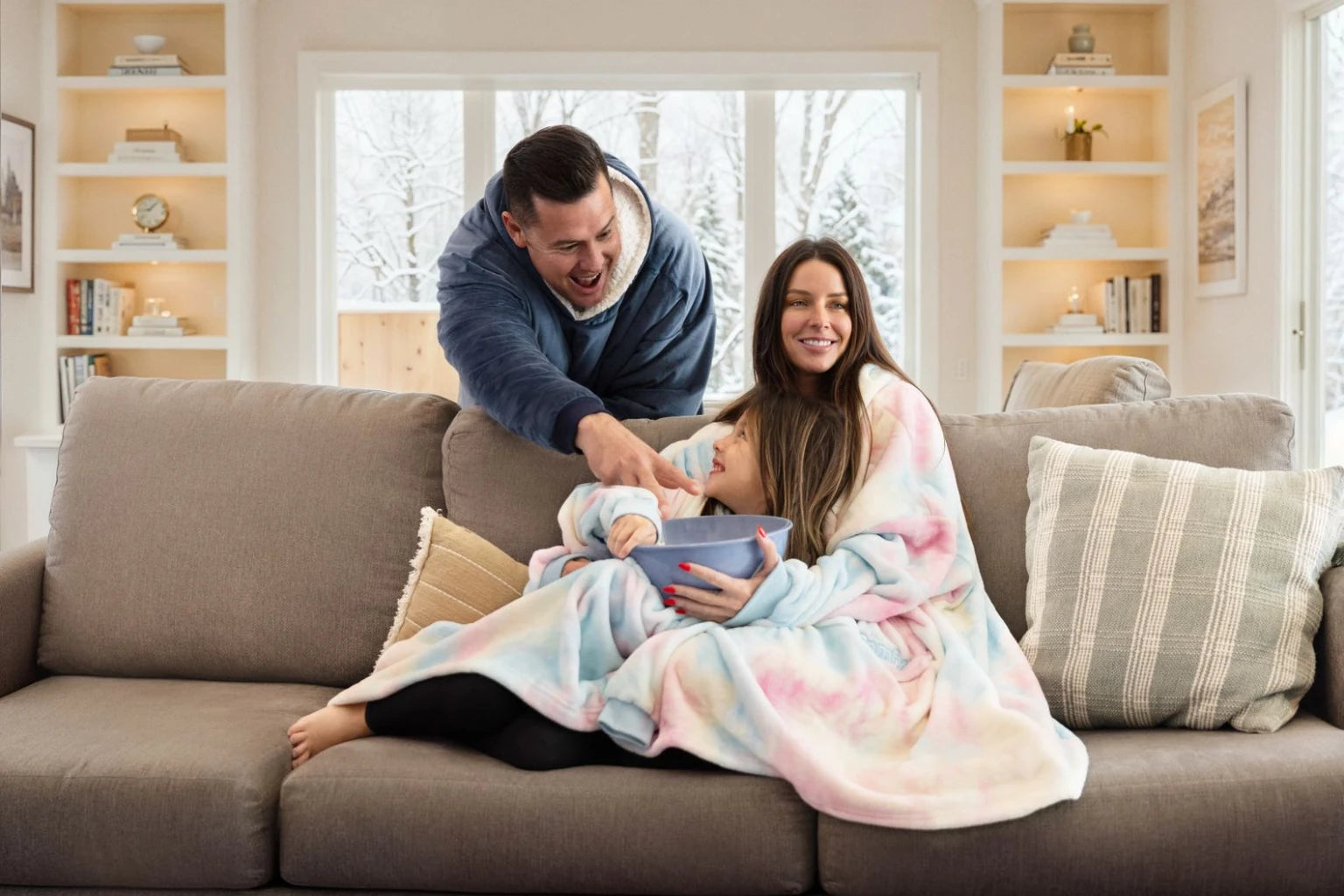 A family relaxing together on a sofa in Original and Junior wearable blankets.