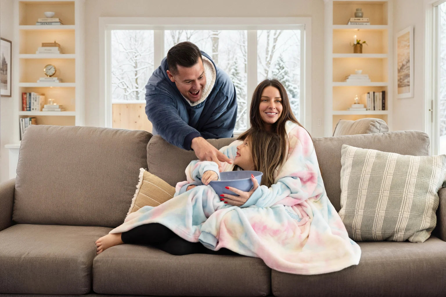 A family relaxing together on a sofa in Original and Dream wearable blankets.